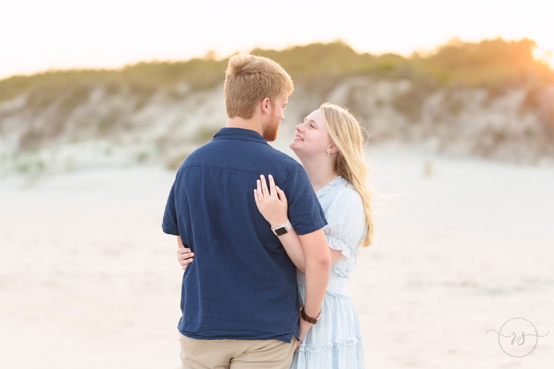 She looks up at him as they hug by the dunes - Huntington Beach State Park