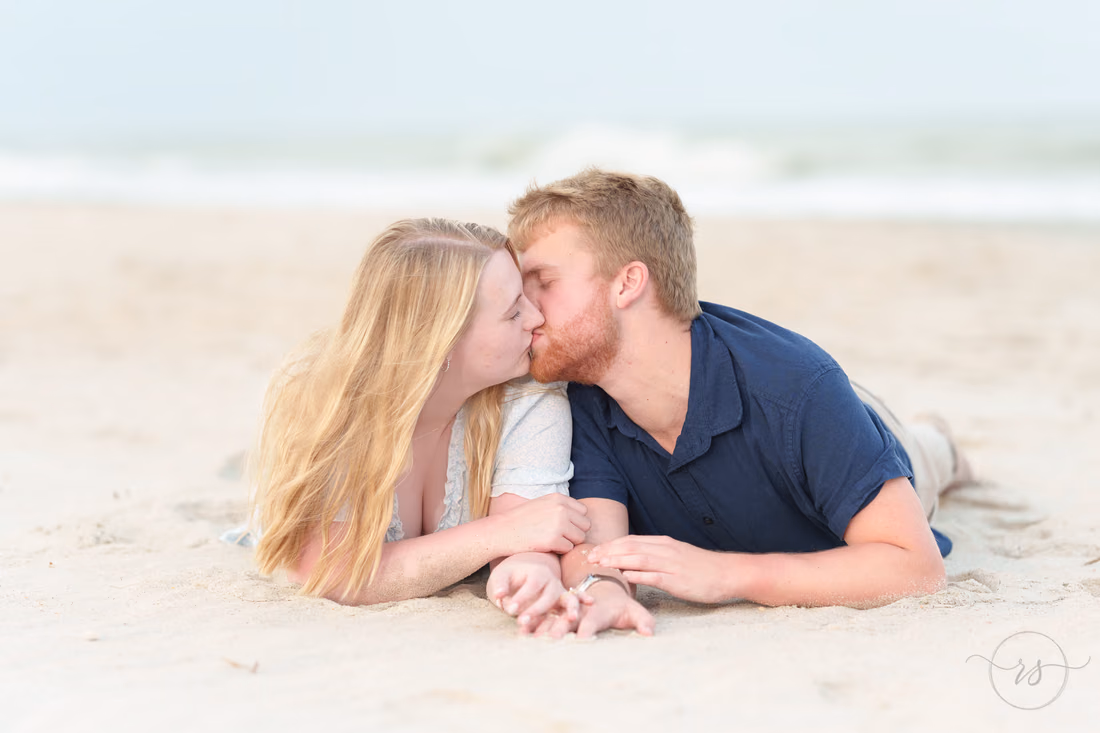 Couple lying in the sand sharing a kiss - Huntington Beach State Park