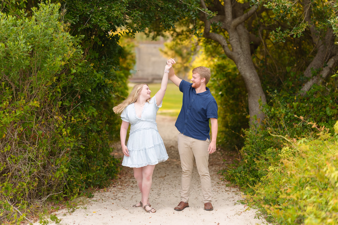 He twirls her on the sandy path under the trees - Huntington Beach State Park