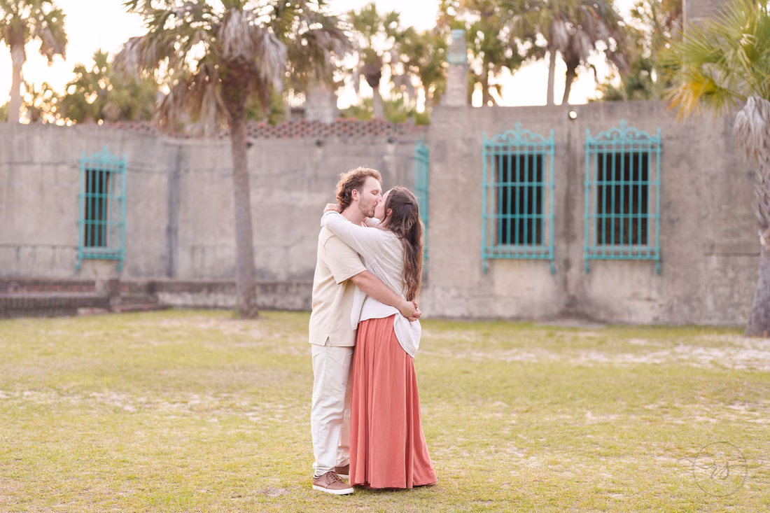 Couple embracing on the lawn in front of Atalaya Castle - Huntington Beach State Park