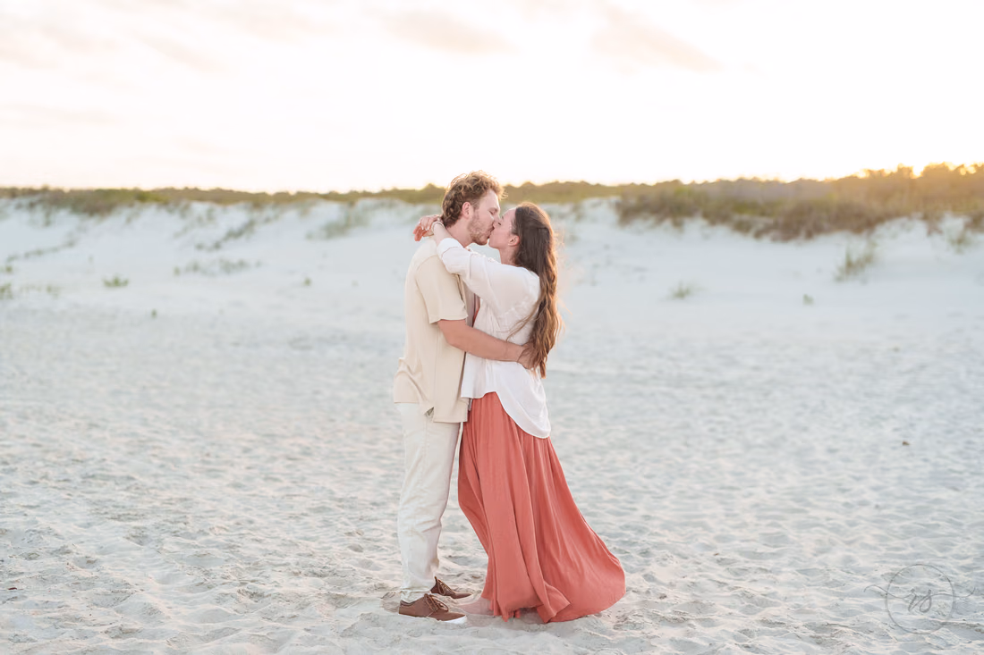 Couple kissing on the sand in front of the dunes - Huntington Beach State Park