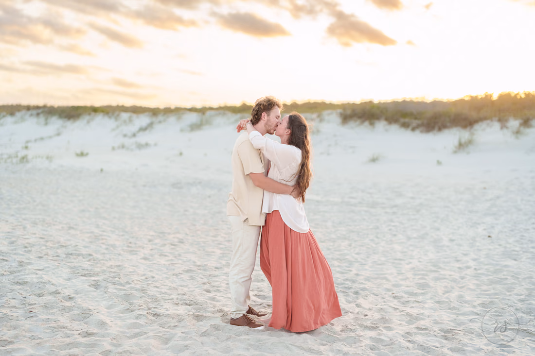 Couple embracing on the open sand under an evening sky - Huntington Beach State Park