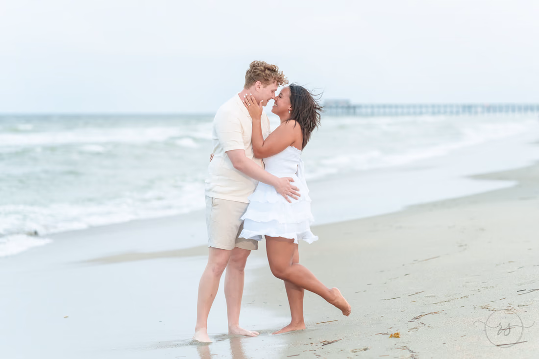 Couple kissing at the water's edge with a pier behind - Myrtle Beach