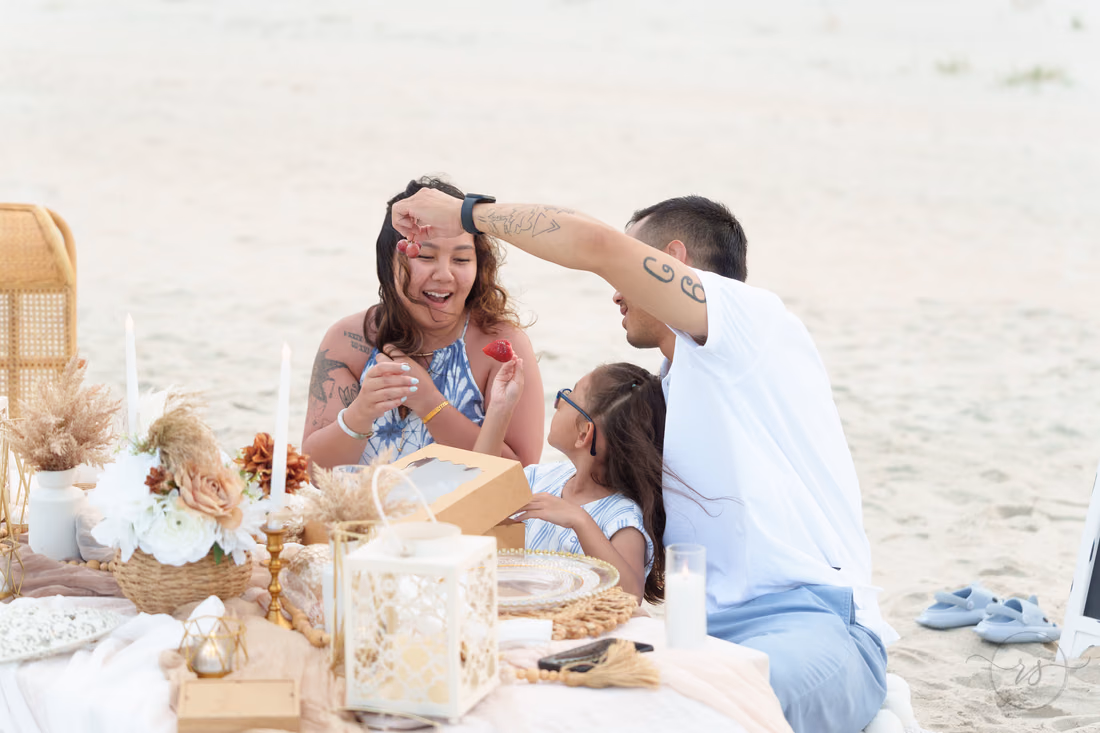 Mom laughing in surprise at the picnic table as dad and daughter look on - Huntington Beach State Park