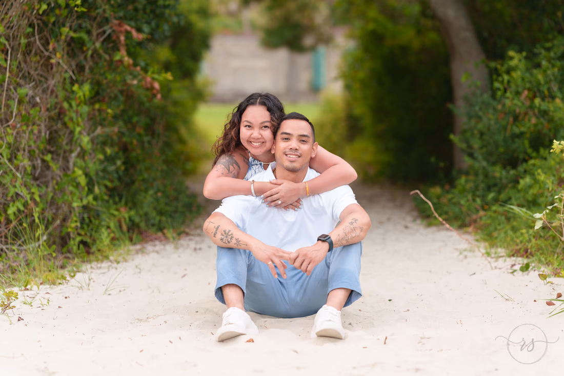 She hugs him from behind on the sandy path - Huntington Beach State Park