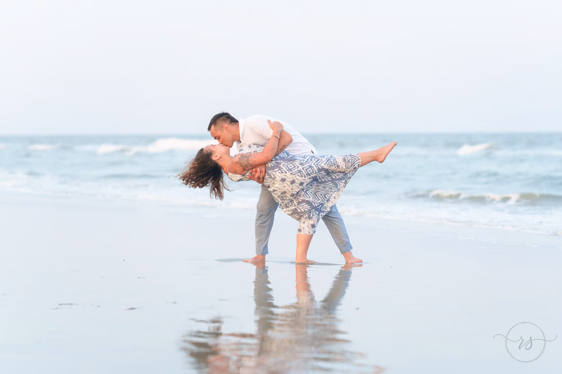 He dips her beside their reflection on the wet sand - Huntington Beach State Park