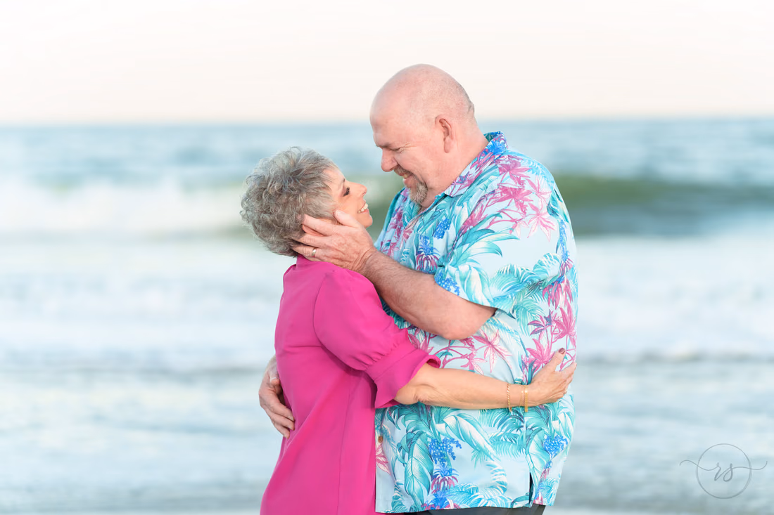 She holds his face as they stand in the surf - Huntington Beach State Park