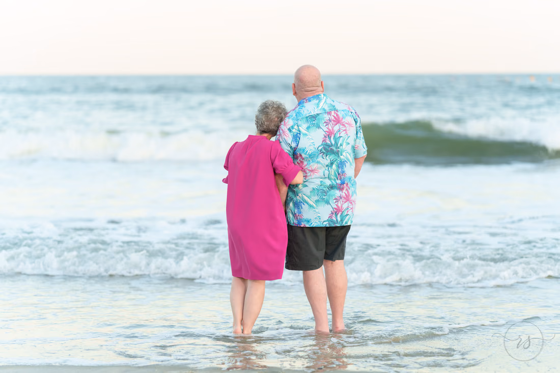 Older couple standing in the surf looking out to sea - Huntington Beach State Park