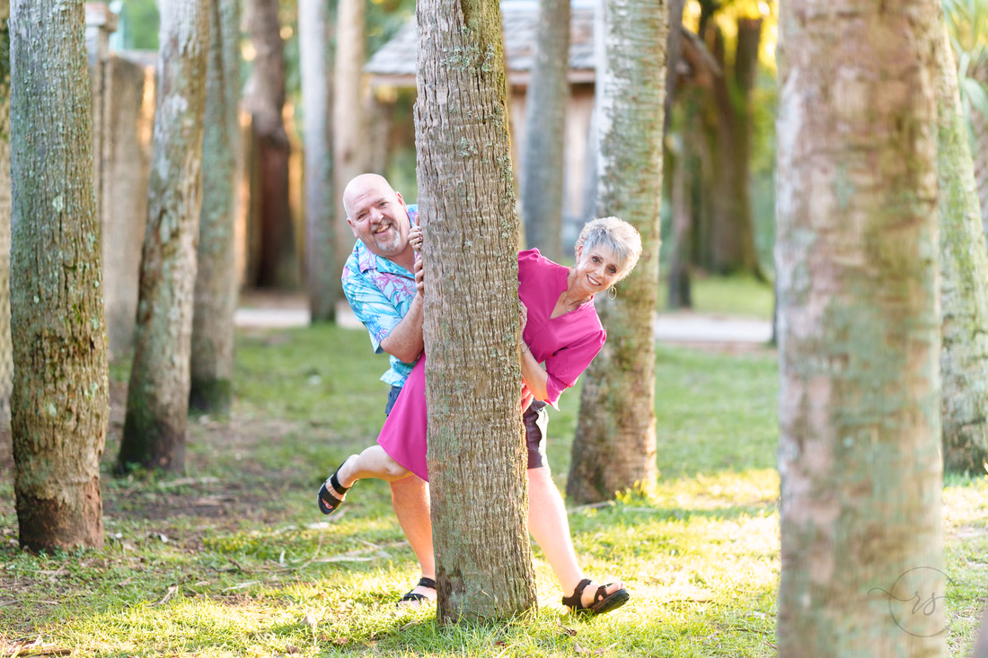 Older couple peeking around a palm tree - Huntington Beach State Park