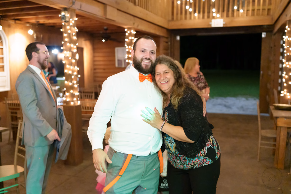 Groom posing with a laughing guest inside the barn at Wildhorse at Parker Farms