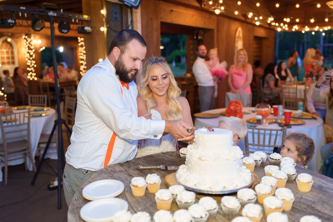 Bride and groom cutting their wedding cake surrounded by cupcakes at Wildhorse at Parker Farms