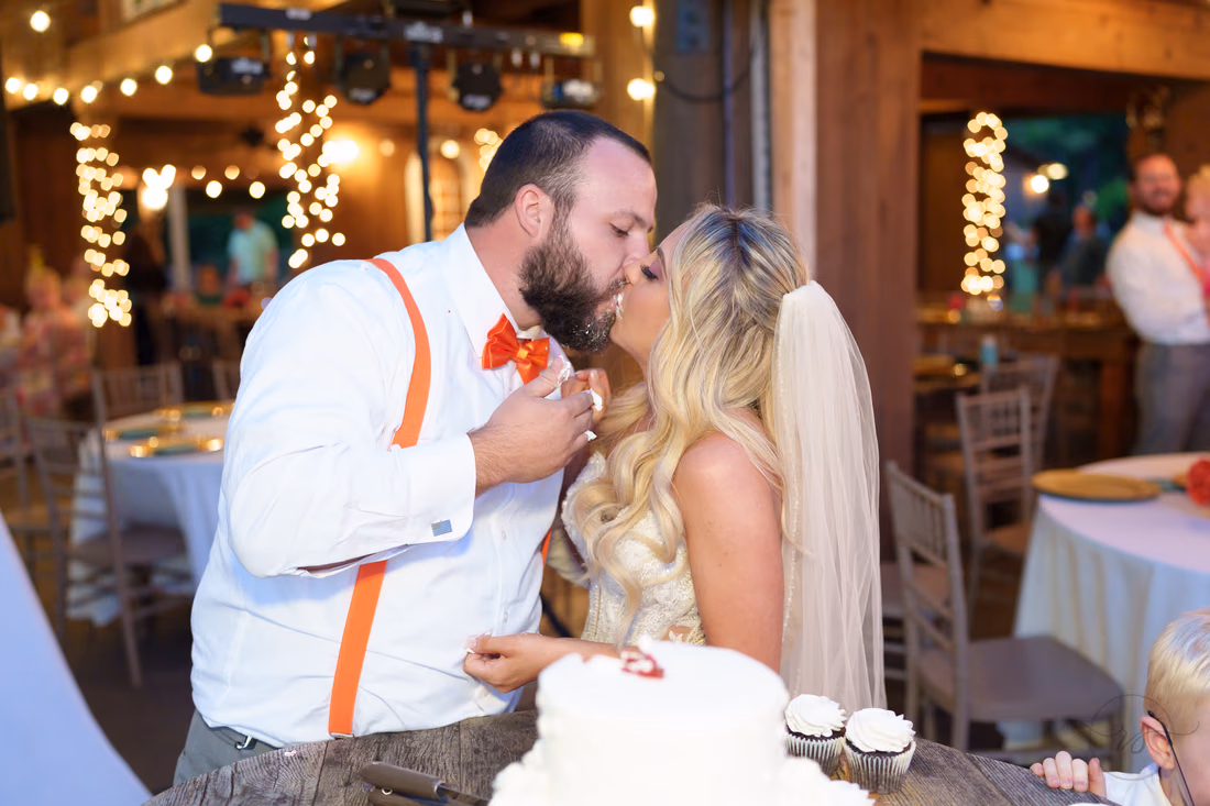 Bride and groom kissing with frosting on their faces after the cake cutting at Wildhorse at Parker Farms