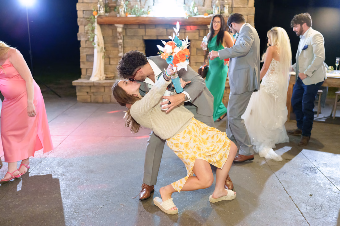 Guest dipping his partner low on the dance floor as the bride looks on at Wildhorse at Parker Farms