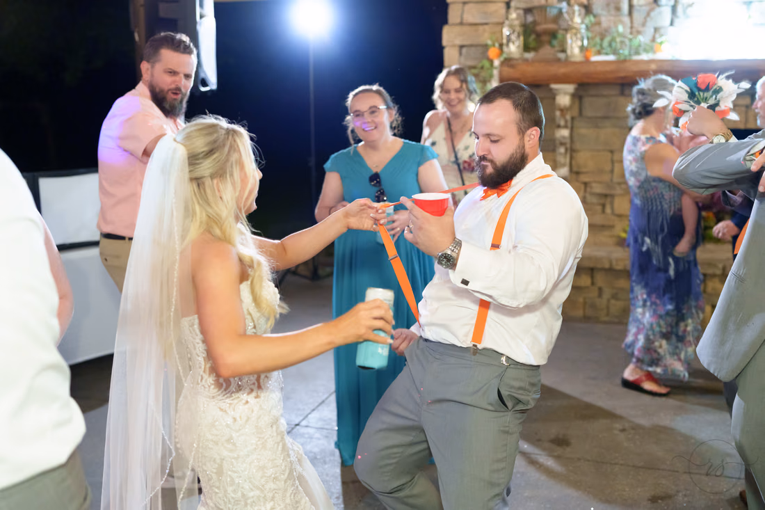 Bride and groom raising their cups as they dance with guests at Wildhorse at Parker Farms