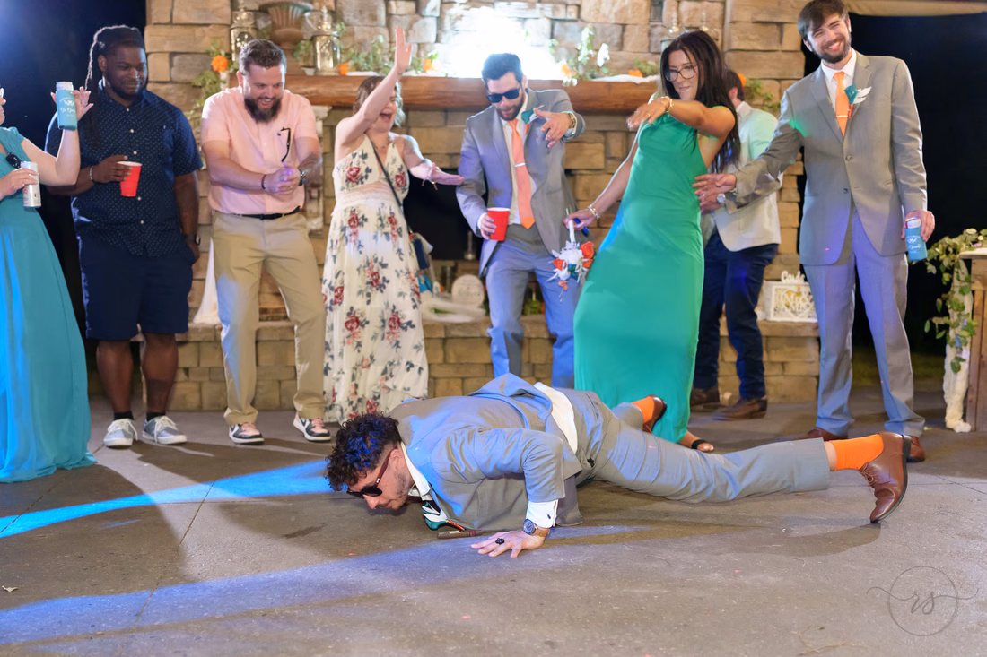 Groomsman doing push-ups on the dance floor as guests cheer at Wildhorse at Parker Farms