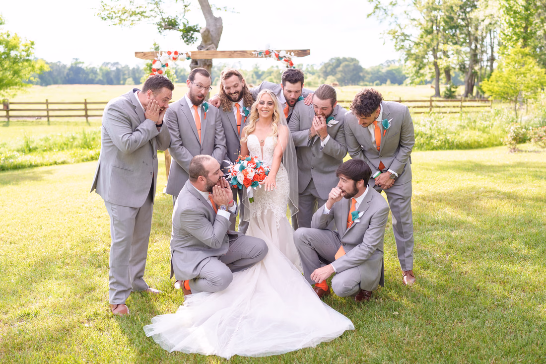 Groomsmen covering their faces in mock surprise around the bride at Wildhorse at Parker Farms