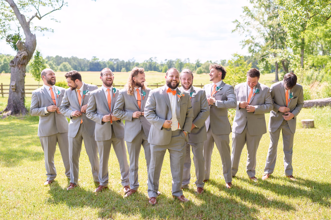 Groomsmen laughing as they adjust their cuffs in front of the pasture at Wildhorse at Parker Farms