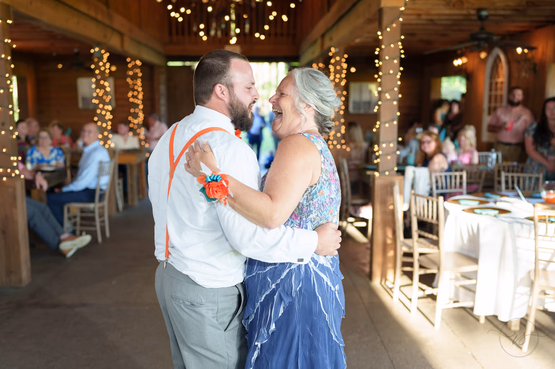 Groom and his mother smiling at each other during their dance in the barn at Wildhorse at Parker Farms