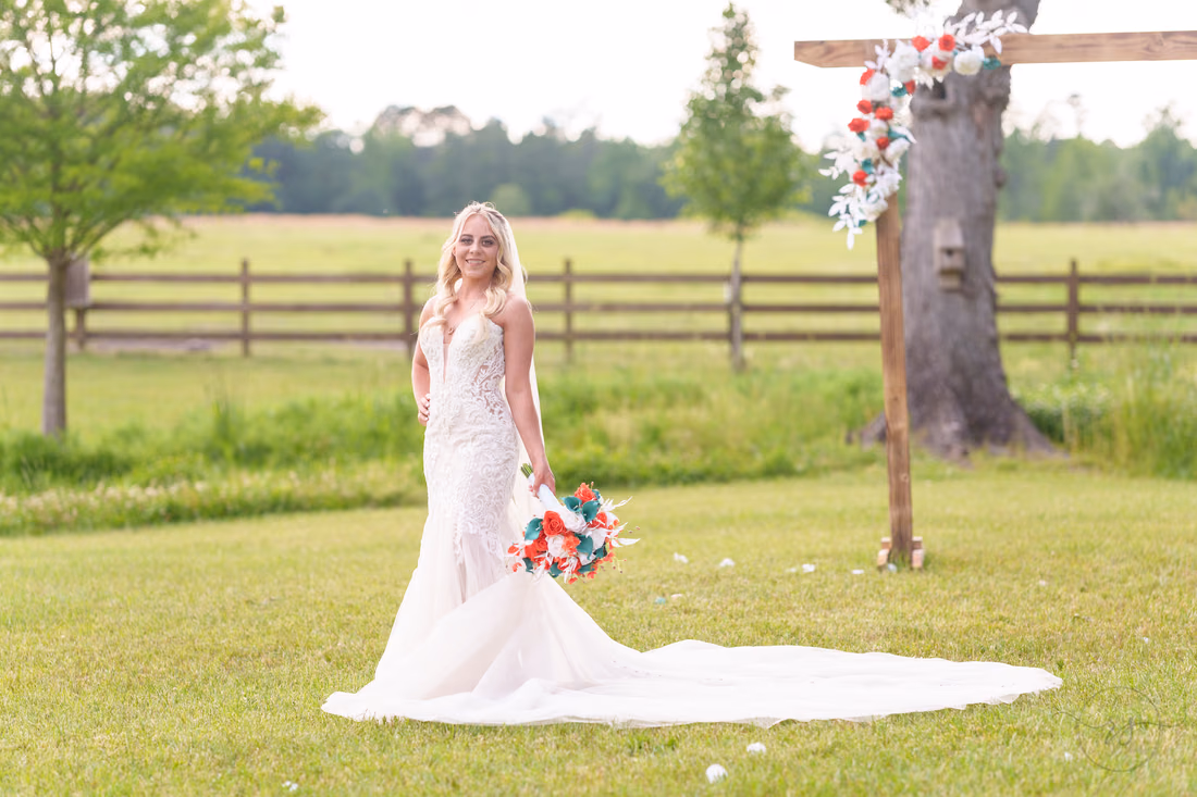 Bride holding her bouquet at her side beside the rustic wooden arch at Wildhorse at Parker Farms