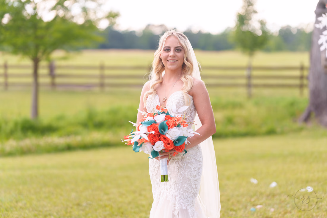 Close portrait of the bride holding her orange and teal bouquet at Wildhorse at Parker Farms