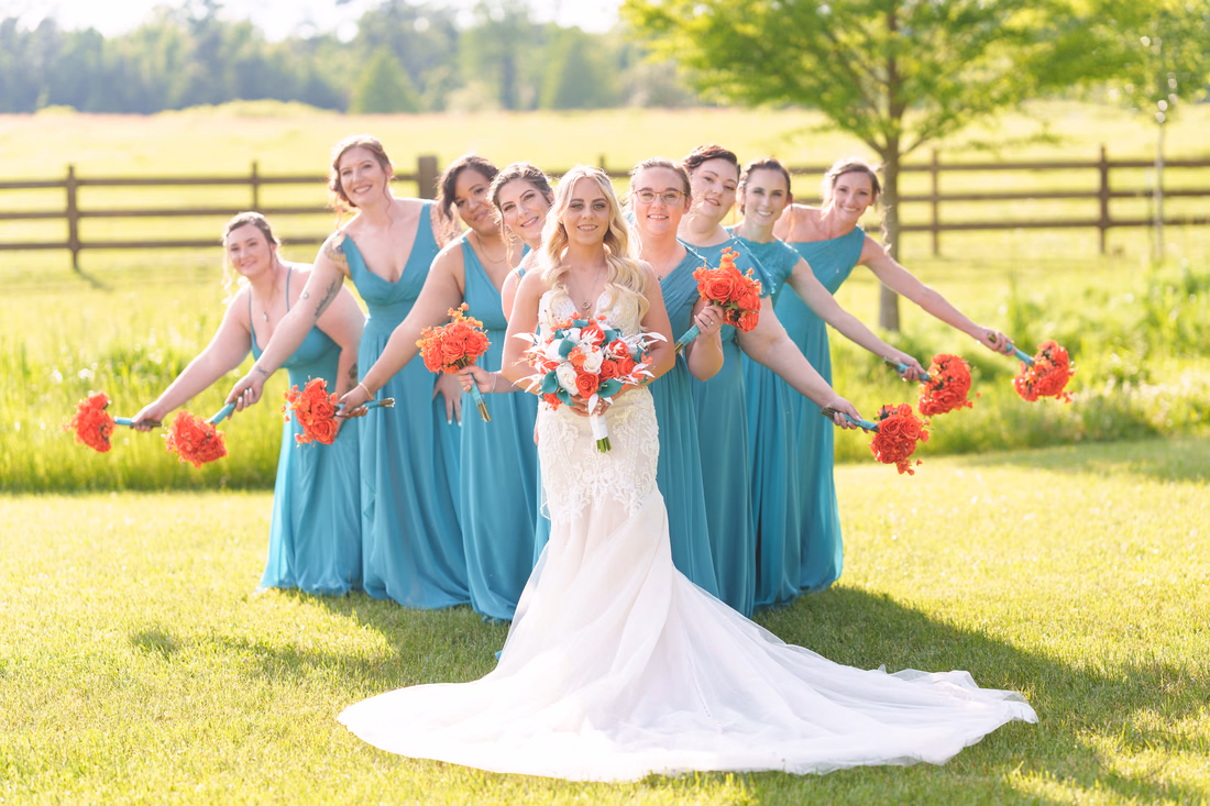 Bridesmaids fanning out their bouquets behind the bride in front of the pasture at Wildhorse at Parker Farms