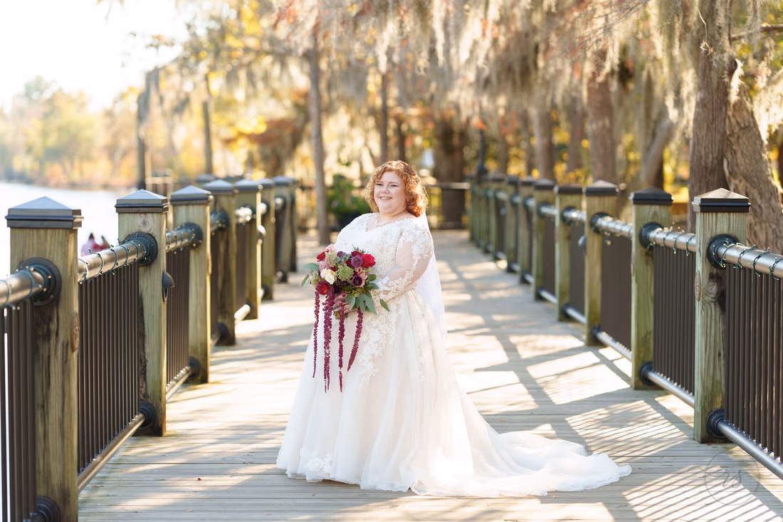 Bride holding her burgundy bouquet on the boardwalk on the Conway Riverwalk