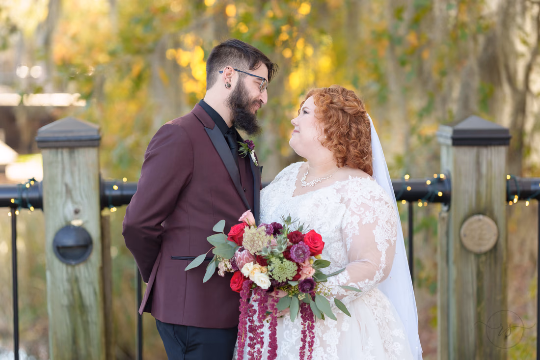 Bride and groom smiling at each other by the railing on the Conway Riverwalk