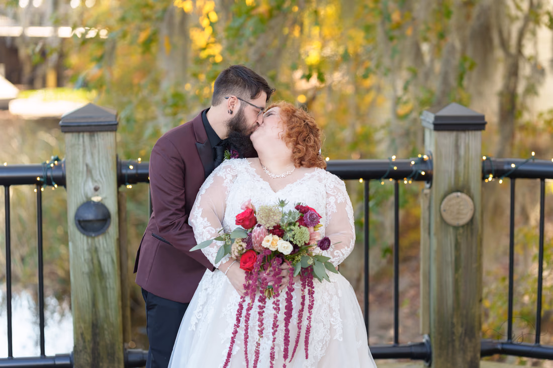 Couple kissing in front of the fall foliage on the Conway Riverwalk