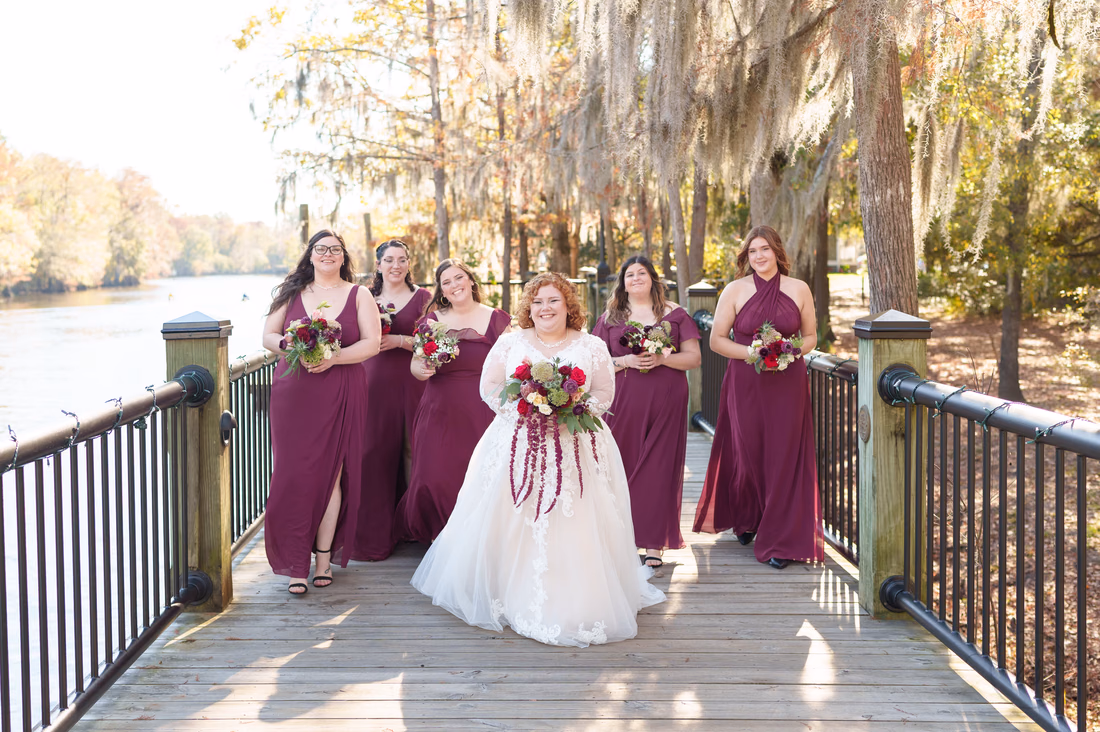 Bride walking toward the camera with her bridesmaids on the boardwalk on the Conway Riverwalk