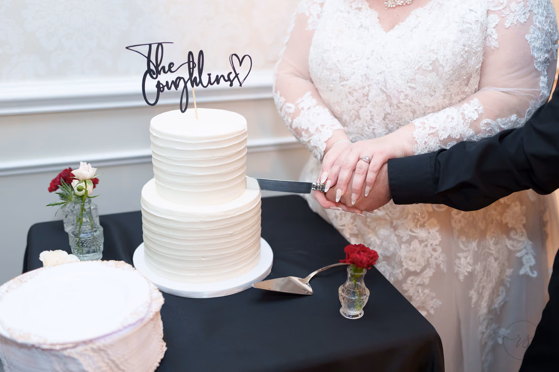 Close-up of the couple's hands cutting the two-tier white cake at The Cypress Inn in Conway