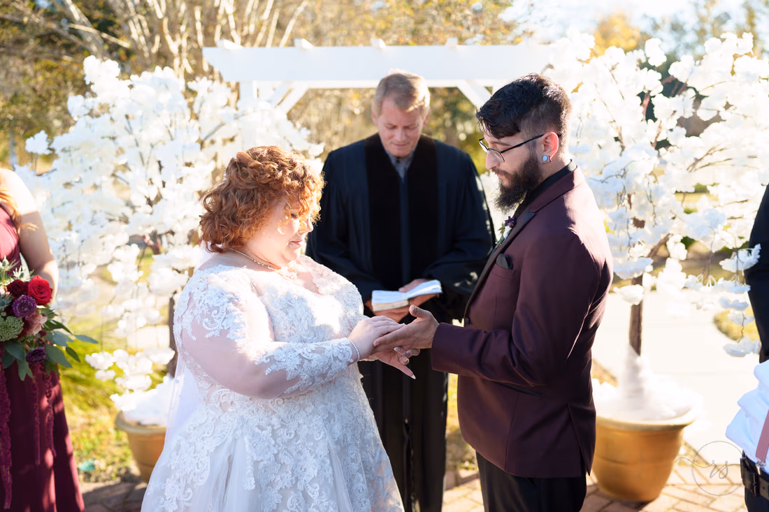 Exchanging rings under the white floral arbor at The Cypress Inn in Conway