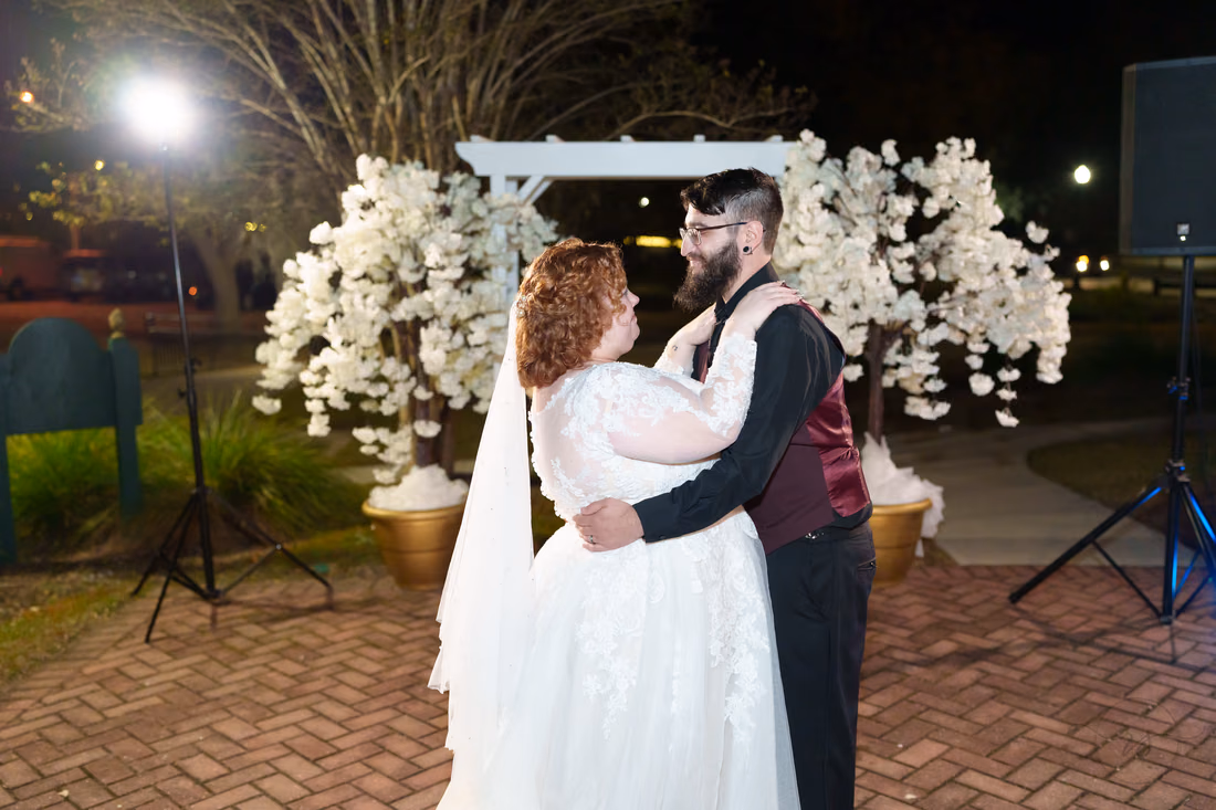 Bride and groom slow dancing by the floral arbor after dark at The Cypress Inn in Conway