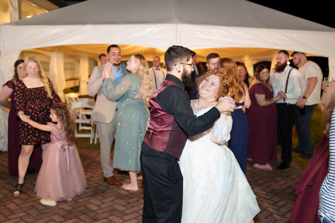 Bride and groom dancing with guests by the tent at night at The Cypress Inn in Conway