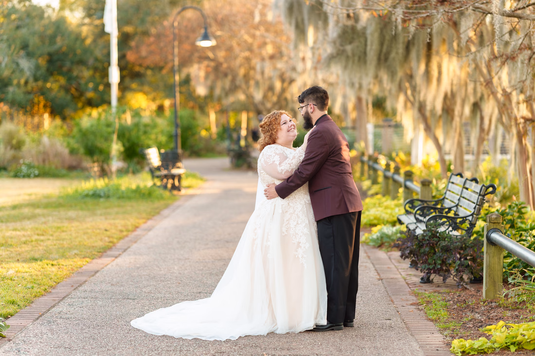 Couple hugging and smiling on the tree-lined walkway on the Conway Riverwalk