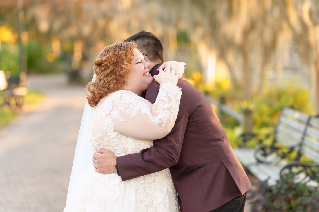 Bride laughs as the groom hugs her on the path on the Conway Riverwalk