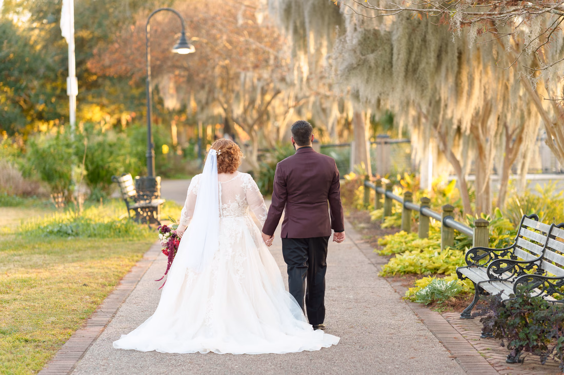 Couple walking away down the moss-covered path at sunset on the Conway Riverwalk