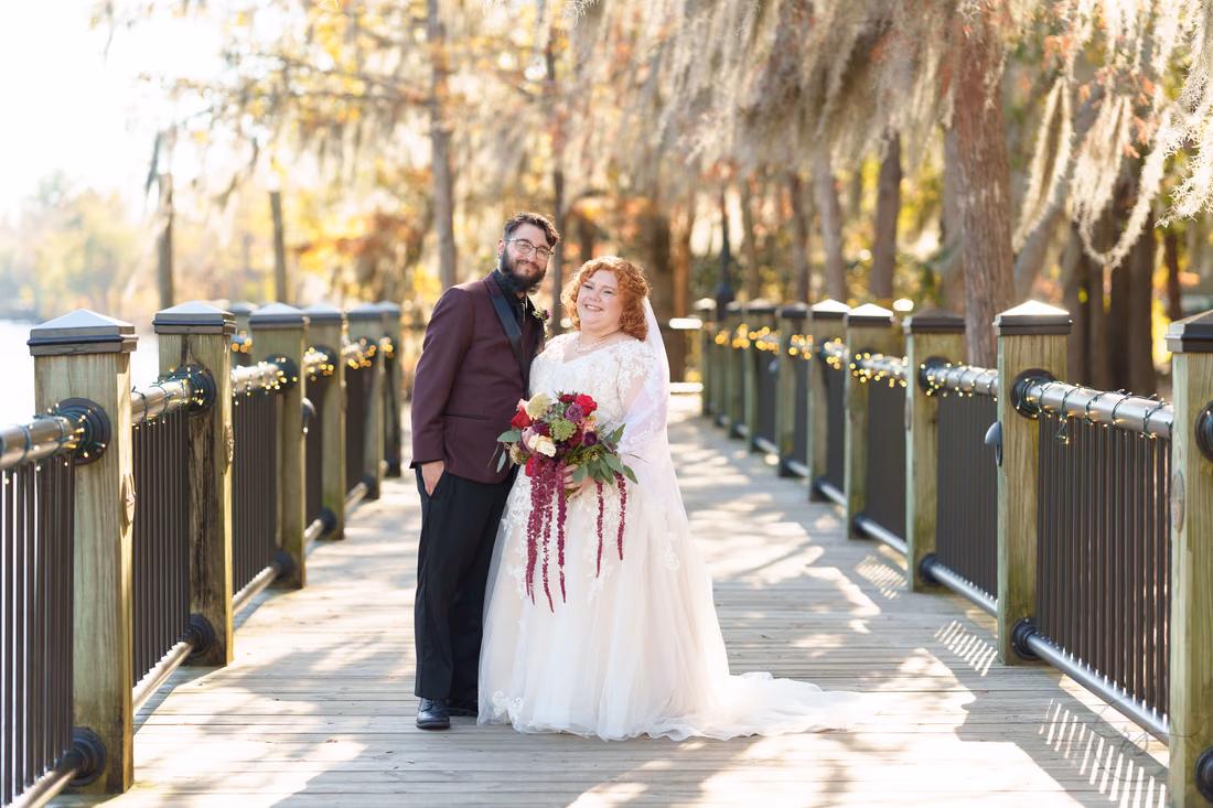 Couple smiling together by the boardwalk railing on the Conway Riverwalk
