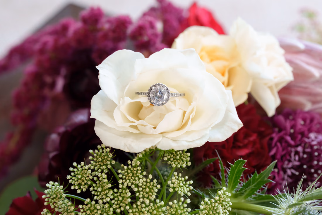 Engagement ring resting in a white rose in the bridal bouquet at The Cypress Inn in Conway