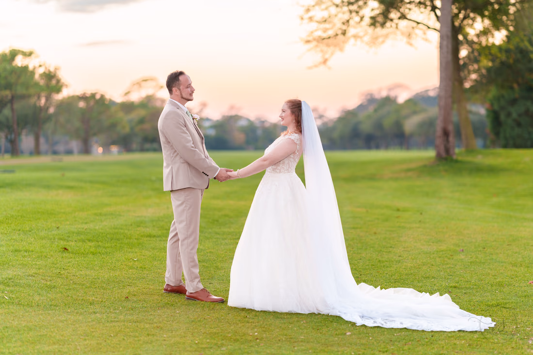 The bride and groom hold hands facing each other on the golf course at Pine Lakes Country Club