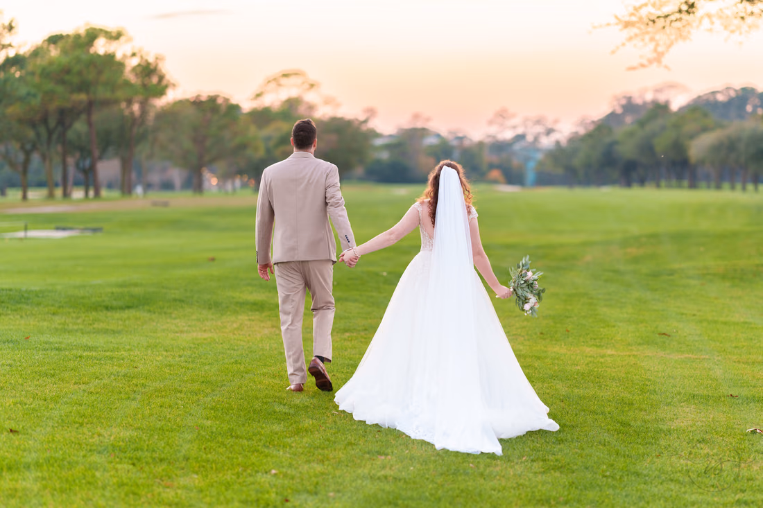 The groom leads the bride across the fairway at dusk at Pine Lakes Country Club