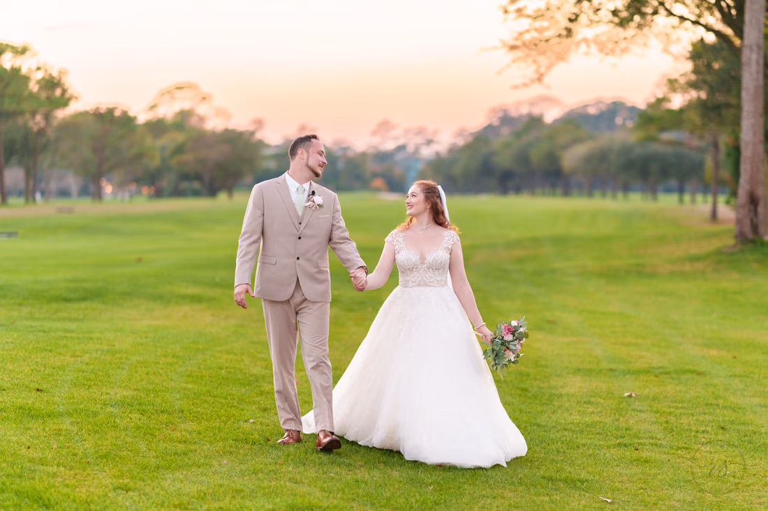 The bride and groom stroll across the golf course at dusk at Pine Lakes Country Club