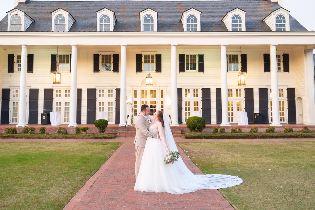 The bride and groom on the brick walk in front of the lit clubhouse after sunset at Pine Lakes Country Club