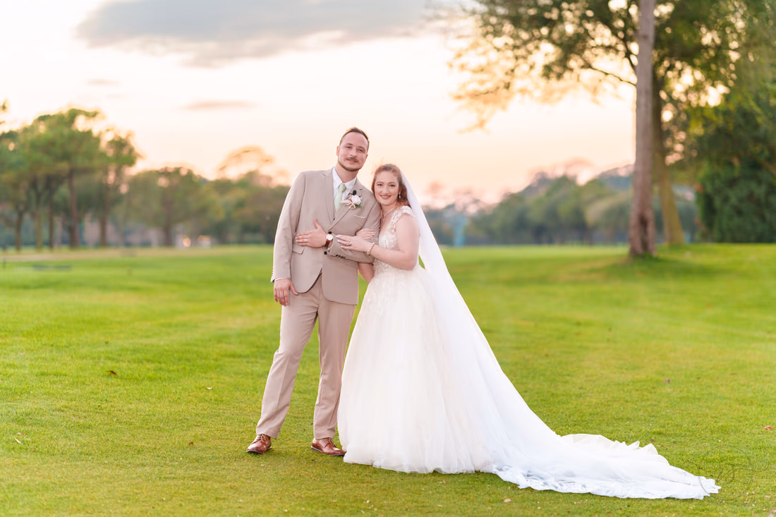 The bride and groom smile together on the golf course after sunset at Pine Lakes Country Club