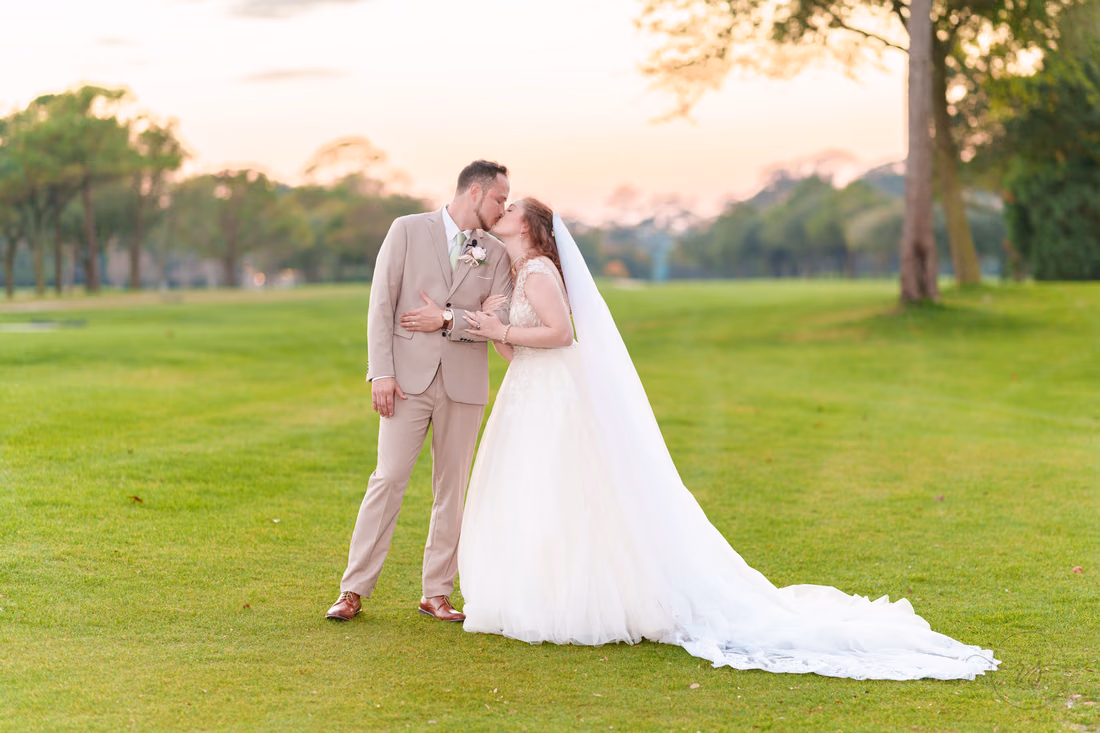 The groom kisses the bride's forehead on the golf course after sunset at Pine Lakes Country Club