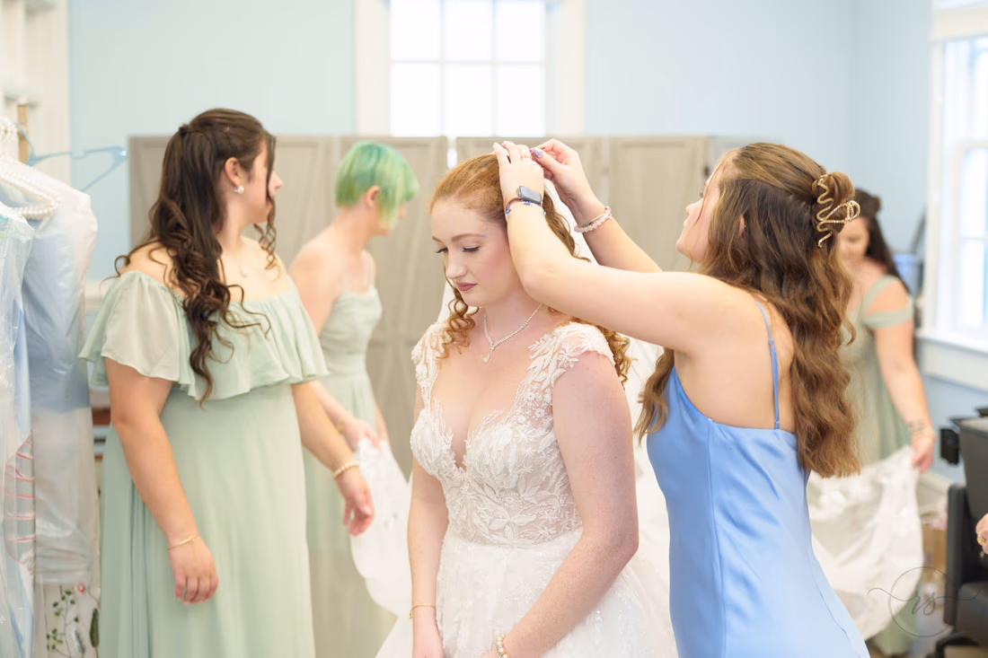 Bridesmaids fix the bride's hair and gown before the ceremony at Pine Lakes Country Club