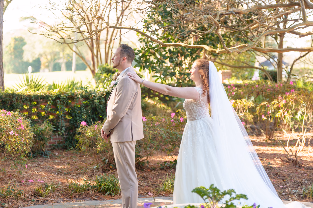 The bride taps the groom on the shoulder for their first look in the garden at Pine Lakes Country Club