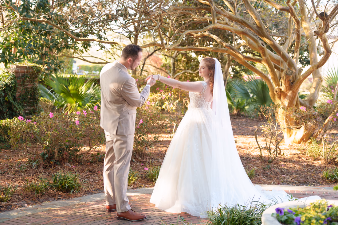 The groom twirls the bride under the trees during their first look at Pine Lakes Country Club