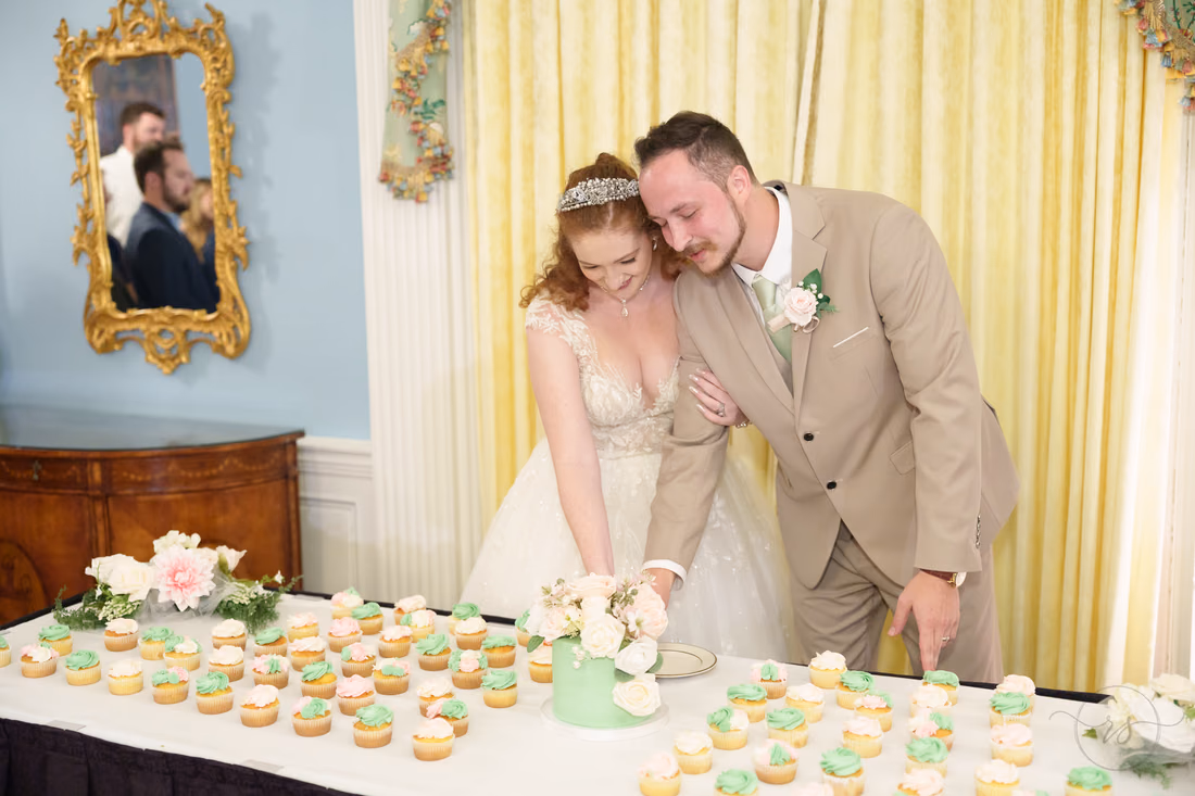 The bride and groom cut the cake at the cupcake table at Pine Lakes Country Club