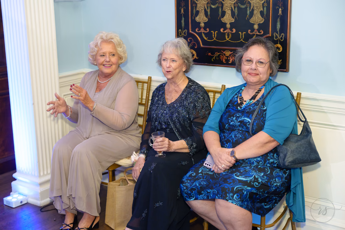 Three women clap and laugh from their seats during the reception at Pine Lakes Country Club
