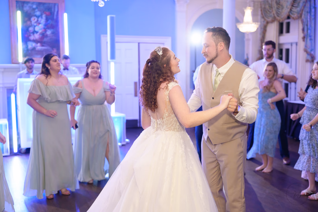 The bride and groom dance with the bridesmaids under colored lights at Pine Lakes Country Club